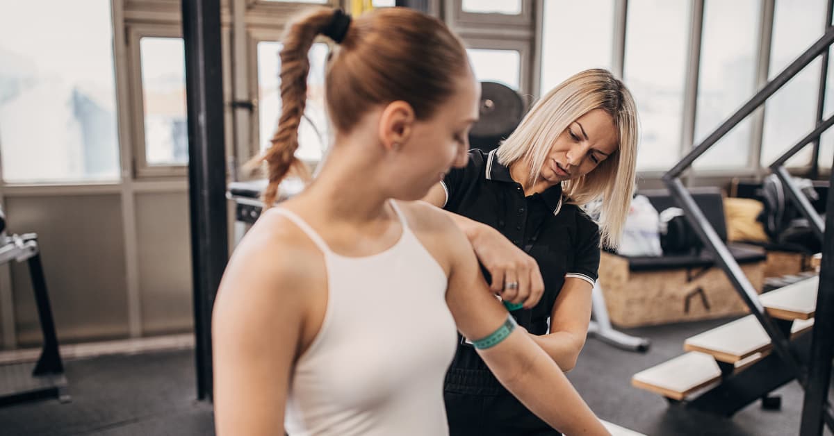 A woman with her trainer, taking measurements.