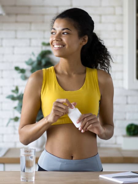 Person in a kitchen holding a bottle | Carnosyn Health and Fitness Amino 